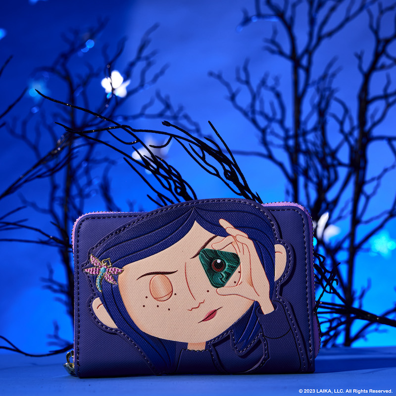 Image of the Coraline zip around wallet, featuring Coraline looking through the seeing stone against a blue background with spooky trees behind it
